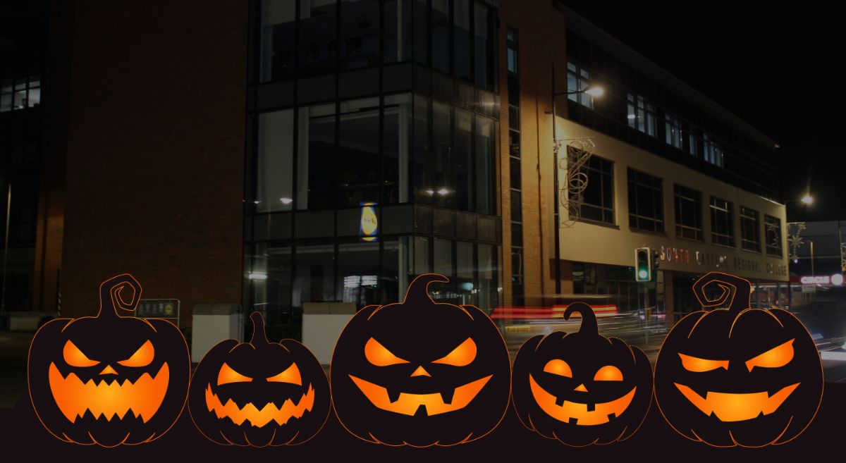 Picture of Downpatrick campus at night with illustrative black pumpkins with orange eyes and mouths