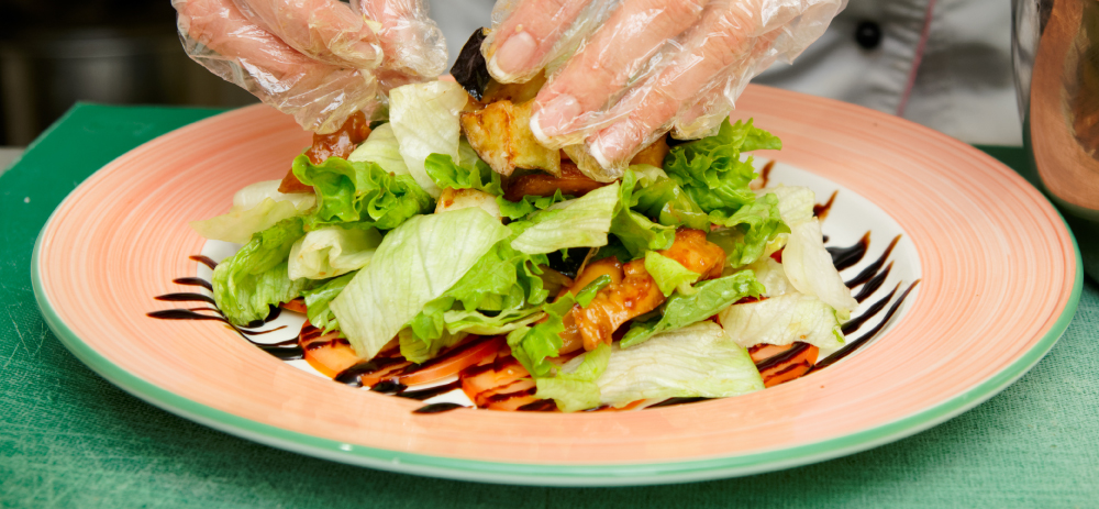 Image of food being plating wearing gloves. 