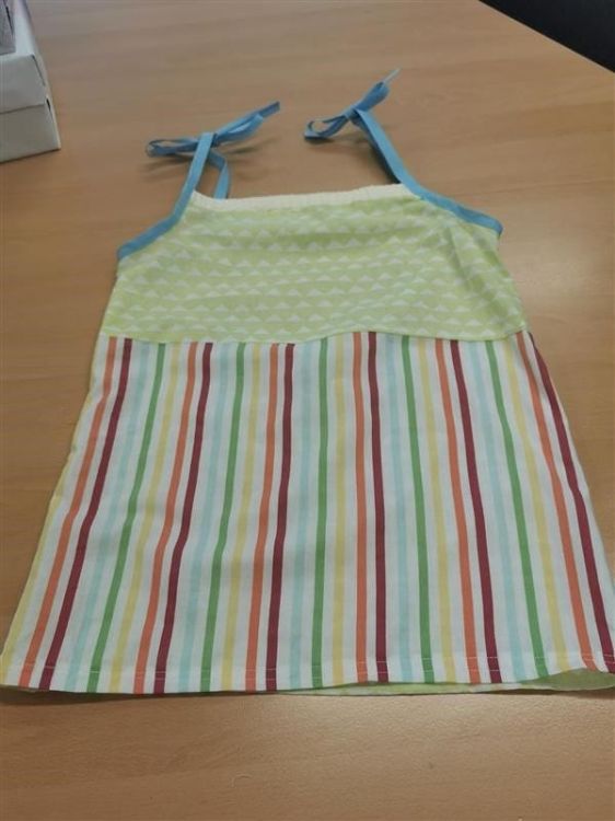 Brightly coloured pillowcase dress displayed on table.with