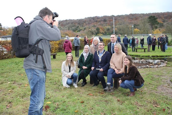 Photograher takes photos of guests posing for picture with guests mingling in garden,