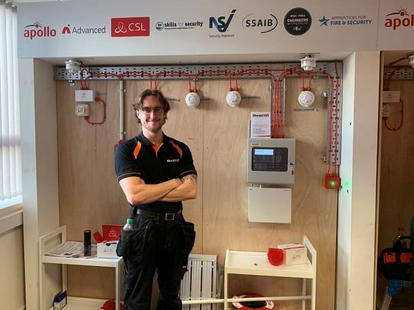 Adam Smylie pictured in front of the fire safety device panel he had to install in the IFSEC Competition.