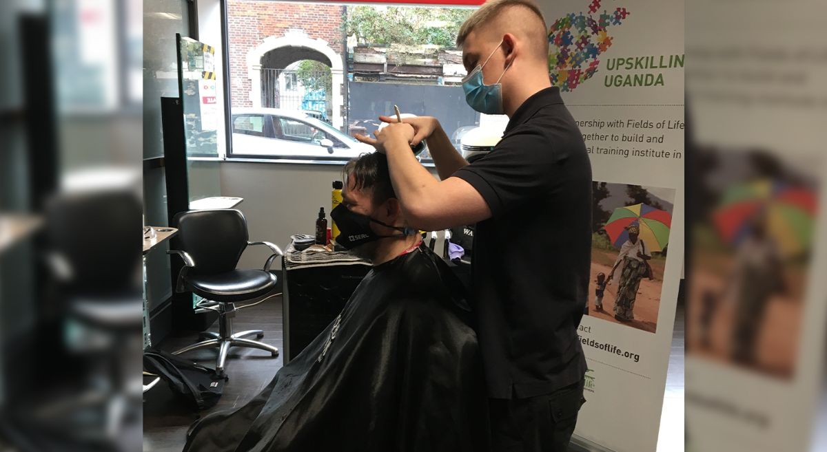 Rudi in the barber seat getting his hair cut by Owen Andrews.