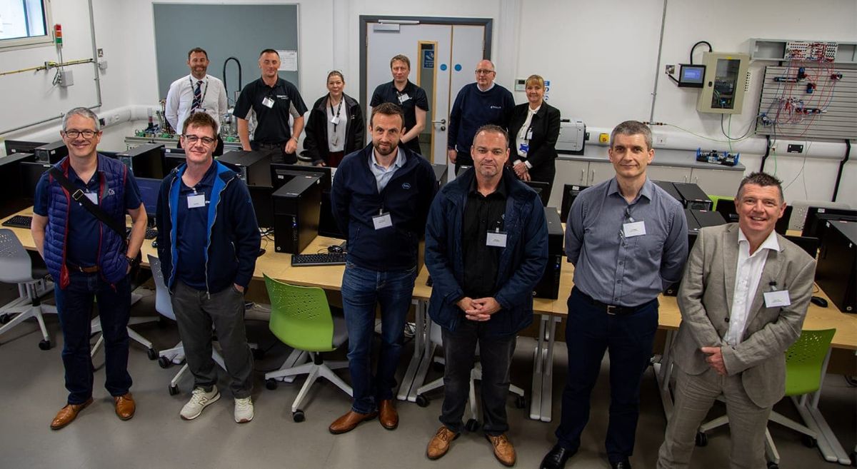 Group of men looking to camera pictured in engineering robotic workshop