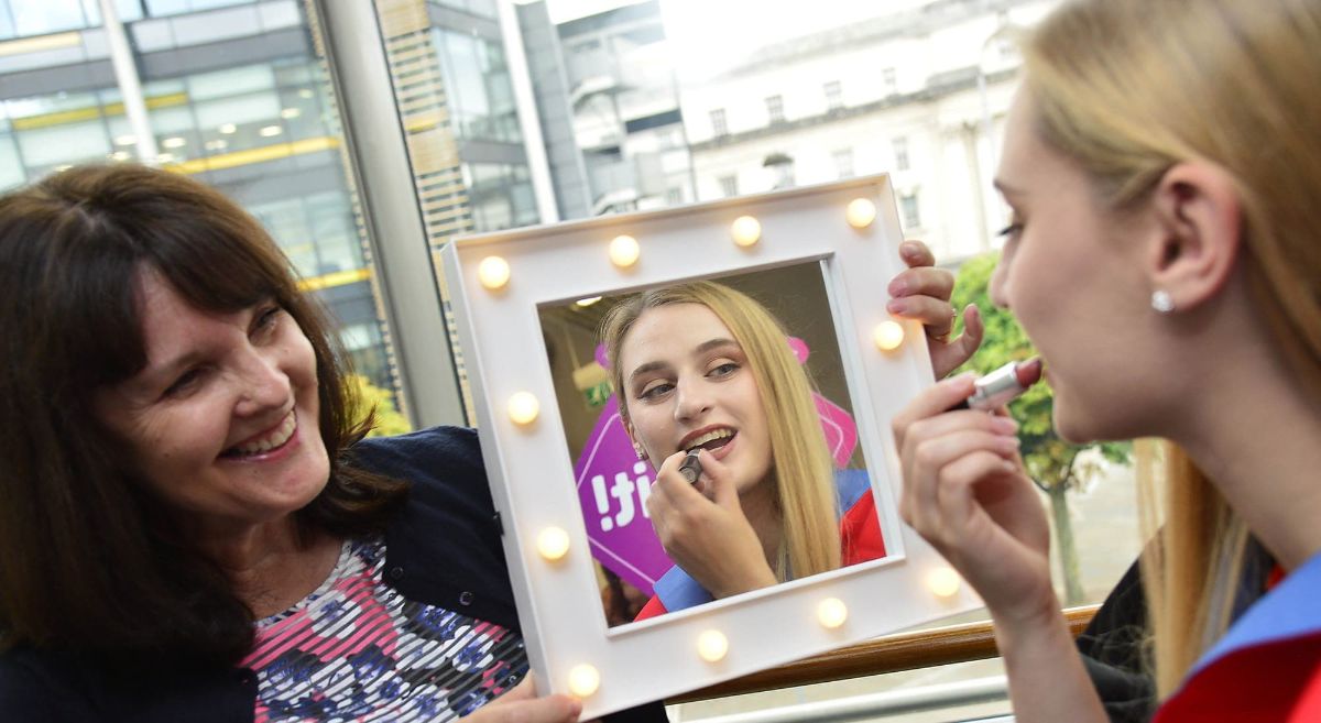 Graduate fixes her makeup whilst proud mum holds mirror