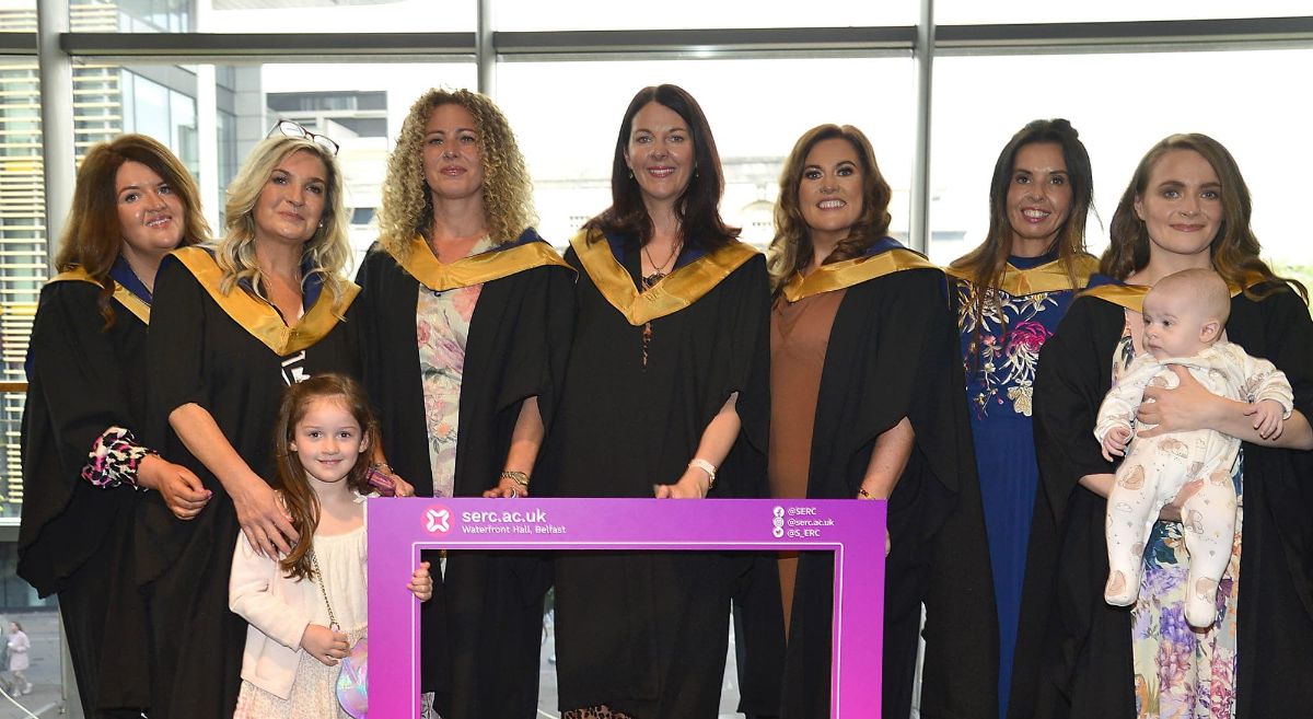 Group of female graduates in gowns with baby and child