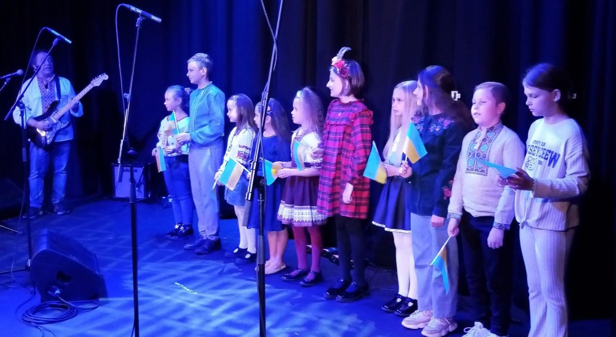 Children on stage singing with guitarist