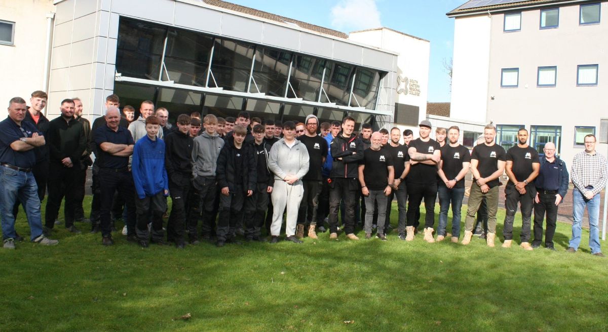 Crowd of male students and lectures standing on grass in front of building