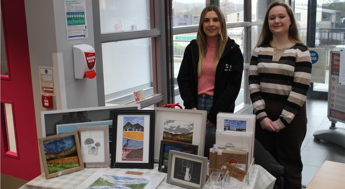 Two people stood behind a table selling art