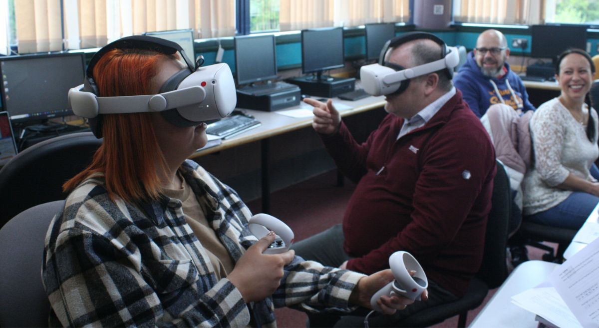 Male and female student wearing VR headsets and holding controllers.