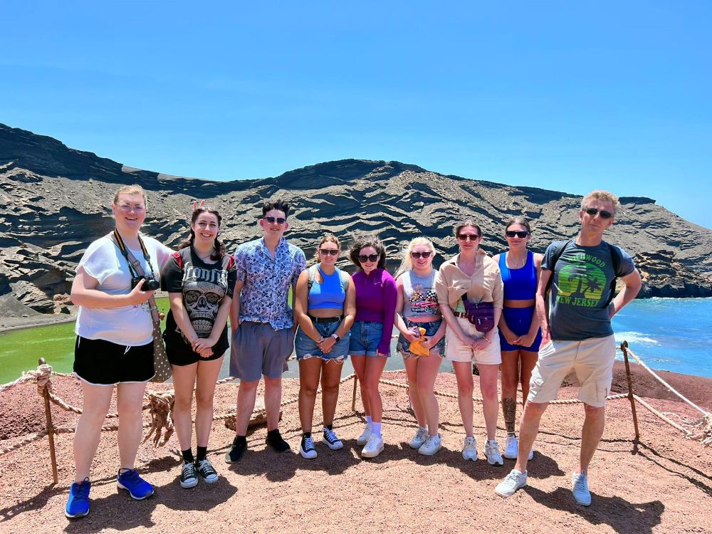 students stood in a row, with scenic mountain backdrop, blue skies