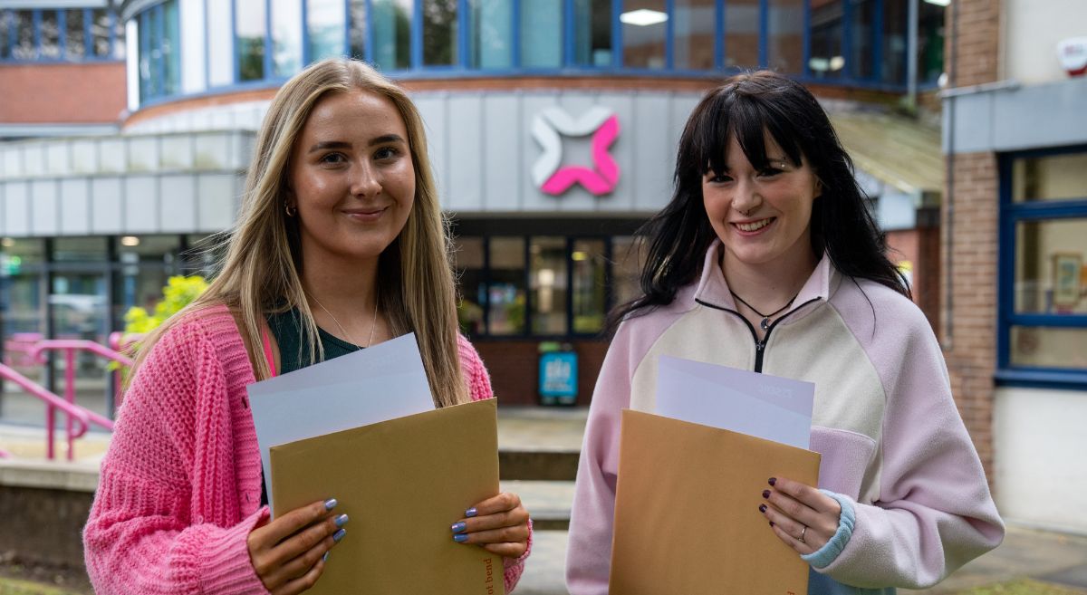 Two females students holding envelopes with results slip pictured outside SERC Bangor Campus