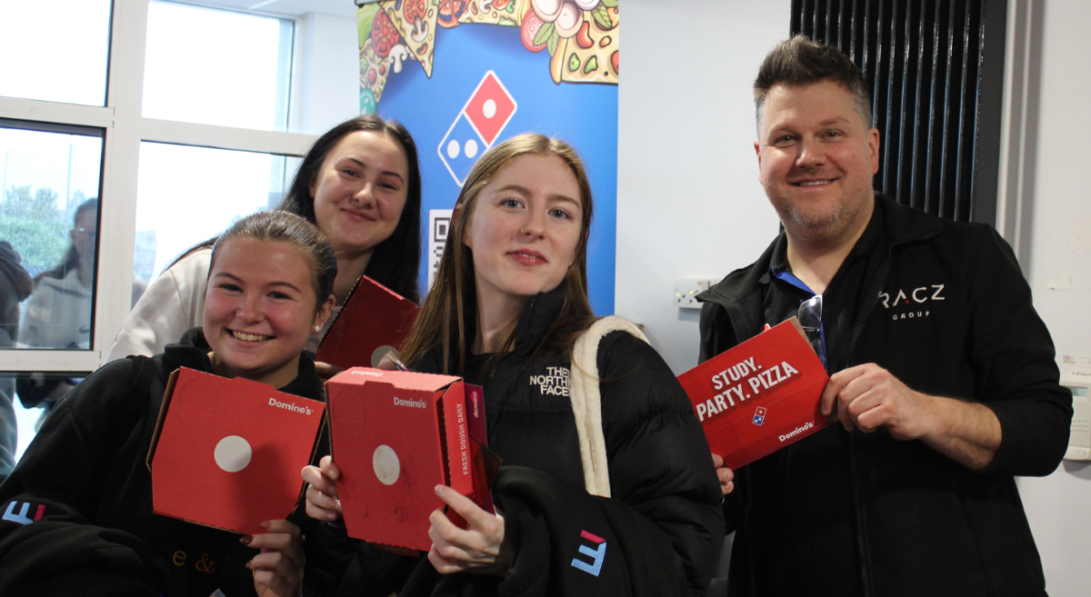 four students holding pizza boxes