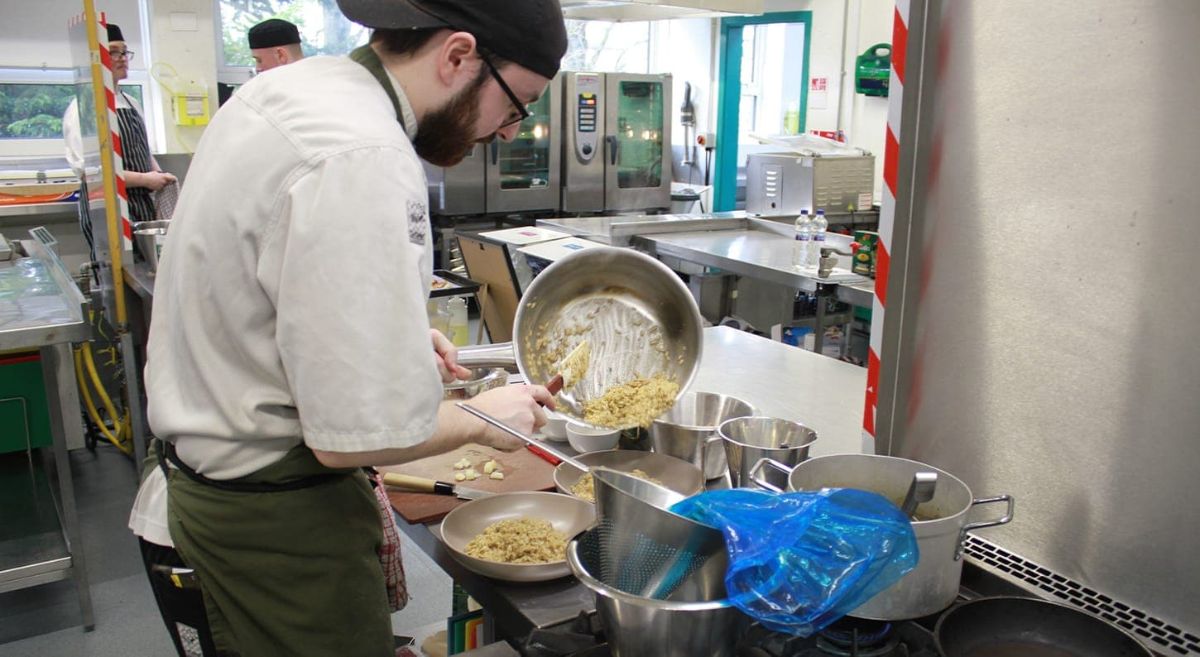 Young male putting Risotto into a bowl.