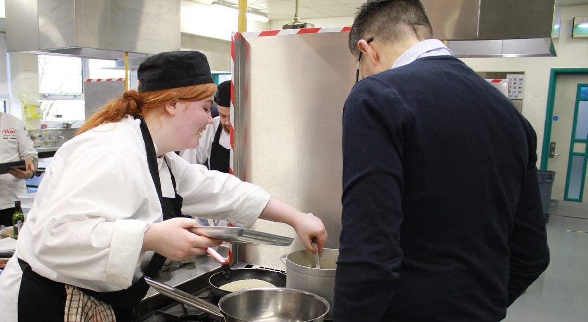 Young female and male looking into a saucepan.