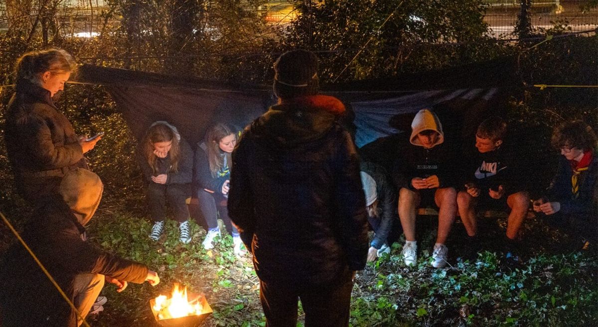 Group of people sitting around a camp fire.