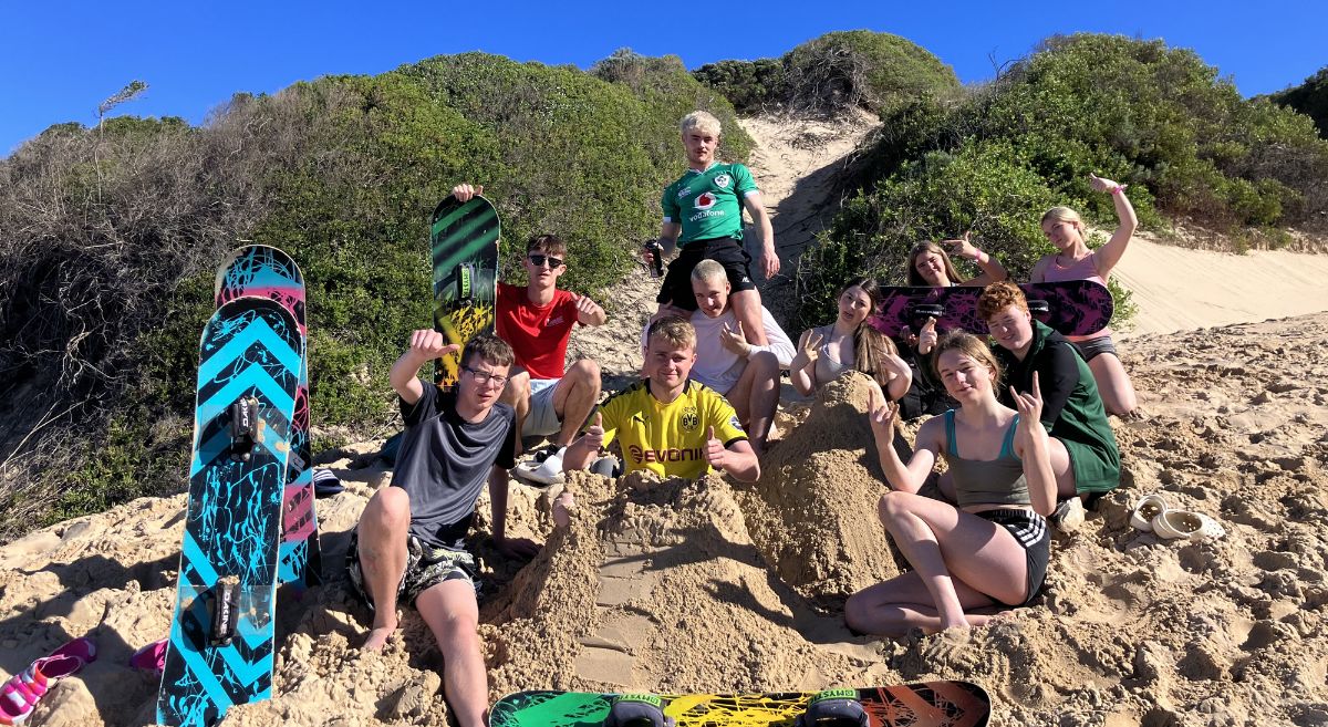 SERC students with surf boards in sand dunes.