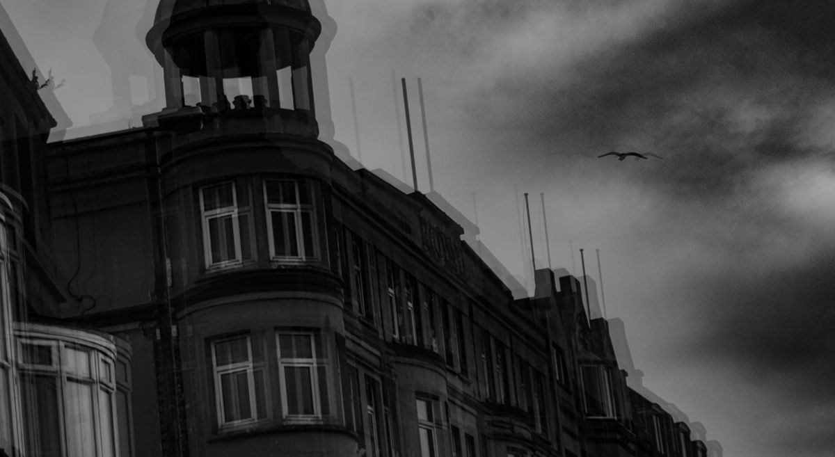 A black and white blurred photo of a building with a tower  and dark clouds in the background