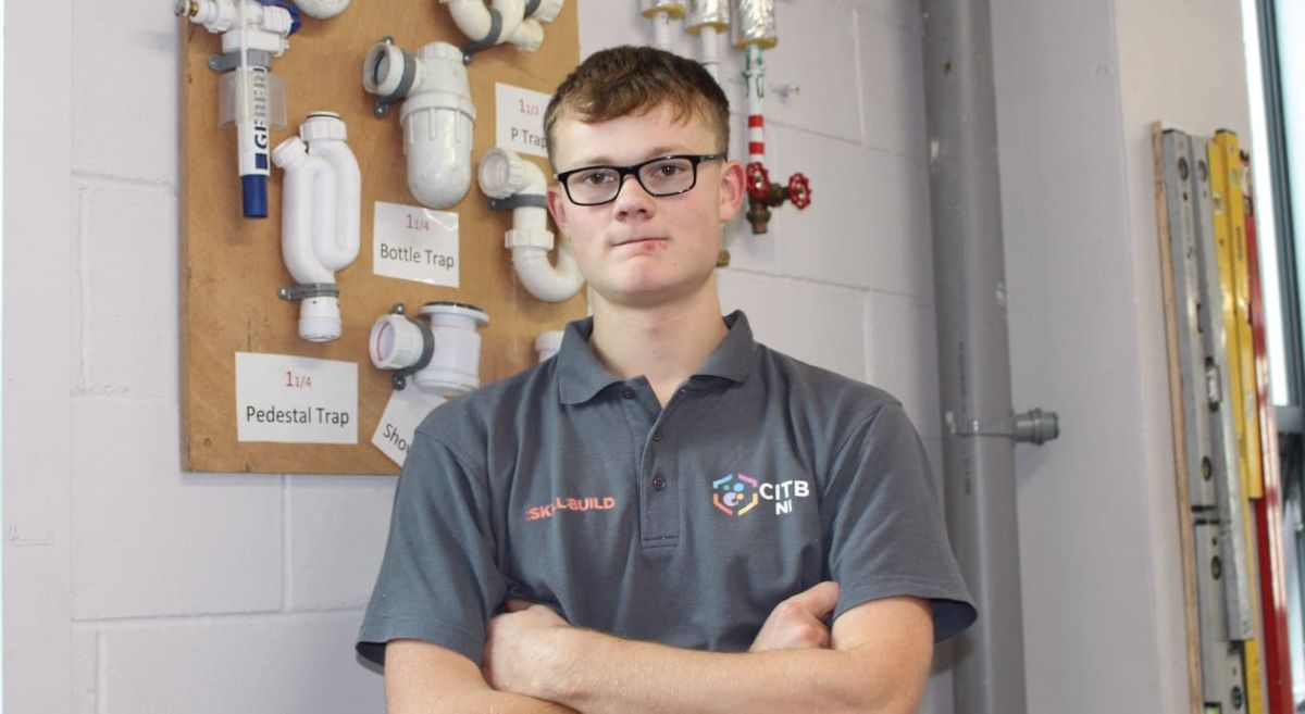 Picture of smiling student with plumbing items in background